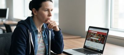 A focused man analyzing Mindvalley reviews on a laptop in a modern workspace.